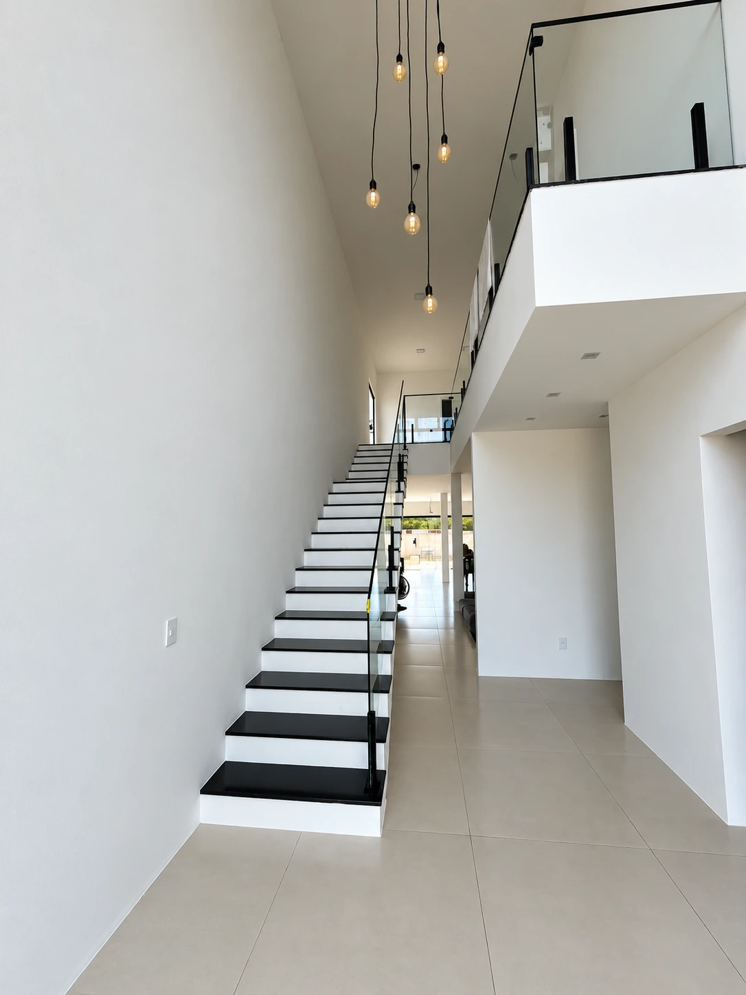 Hall de entrada da Casa Branca, com pé-direito duplo, escada de degraus pretos e pendentes suspensos